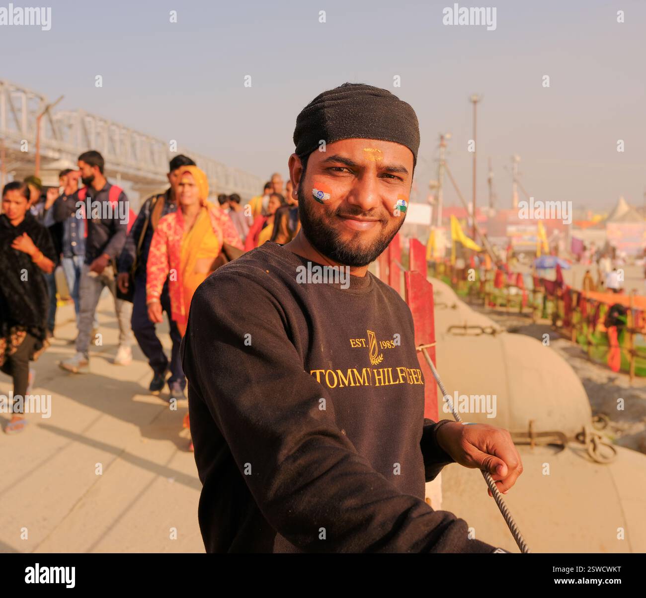 Ein lächelnder Mann mit der Indianerfahne auf seinem Gesicht während der Maha Kumbh Mela in Prayagraj, Indien, die den Unabhängigkeitstag feierte. Stockfoto