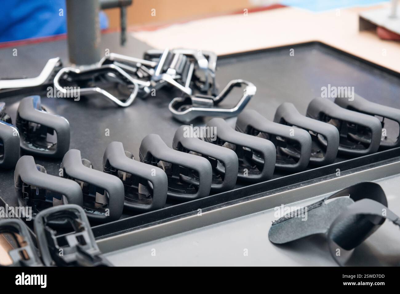 Produktionslinie mit Komponenten für Fahrradsitze in verschiedenen Stufen, die ordentlich auf einer metallischen Oberfläche angeordnet sind Stockfoto