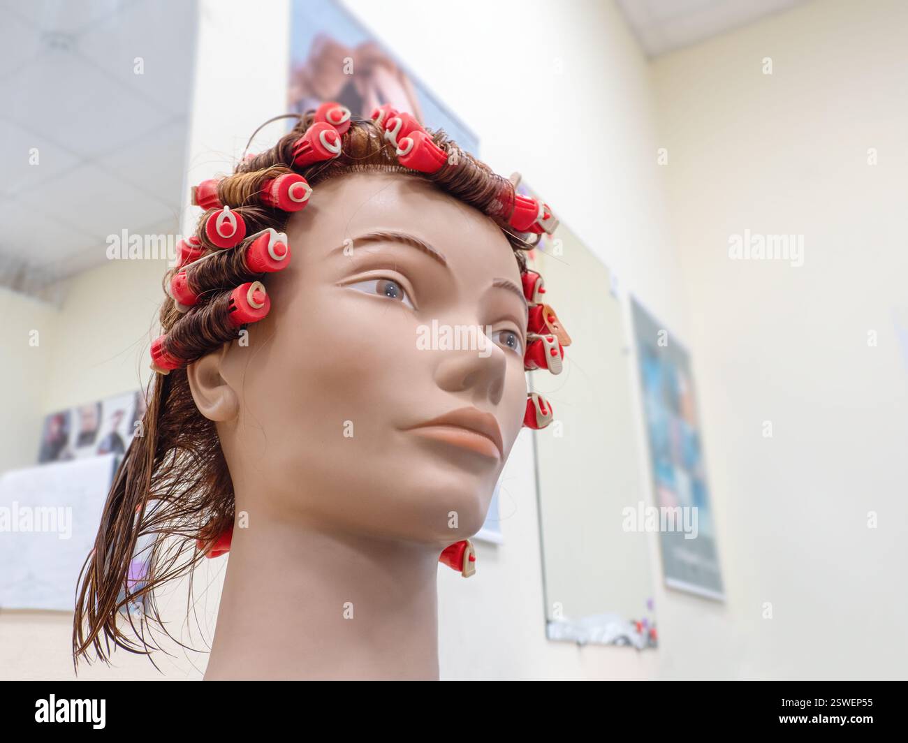 Perm-Training an einer Schaufensterpuppe in der Friseurschule Stockfoto