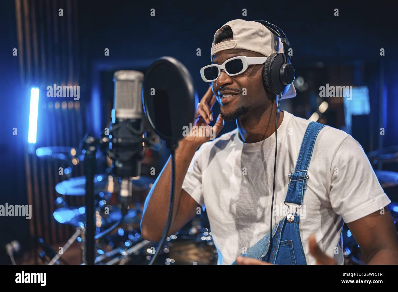 Junger, stilvoller Sänger, der den kreativen Prozess der Aufnahme eines neuen Hits in einem professionellen Musikstudio voller Inspiration genießt Stockfoto Junger, stilvoller Sänger, der den kreativen Prozess der Aufnahme eines neuen Hits in einem professionellen Musikstudio voller Inspiration genießt Stockfoto