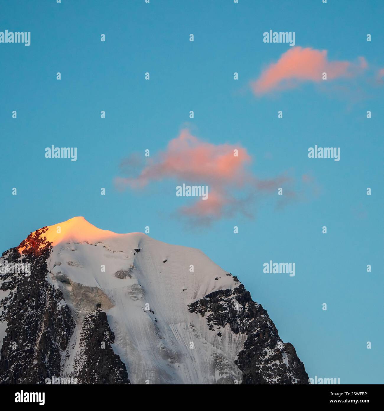Oben schwarze Felsen im goldenen Sonnenschein am Abend und weißschneebedeckten spitzen Gipfel. Stimmungsvolle Landschaft mit hoch verschneiten Bergen mit peake Stockfoto