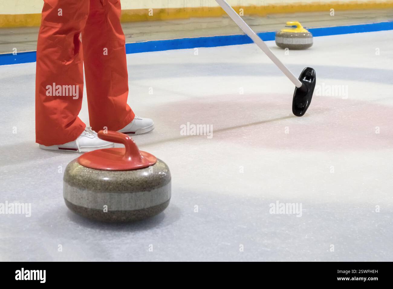 Besen und Stein zum Eisstockschießen auf einer Eisbahn. Stockfoto