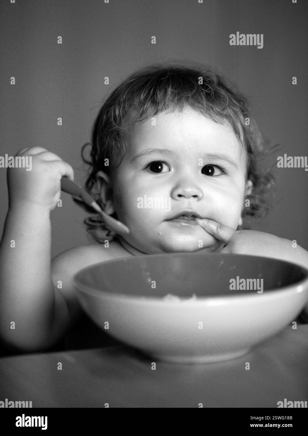 Lustige Baby Essen selbst mit einem Löffel in der Küche. Gesunde Ernährung für Kinder. Stockfoto
