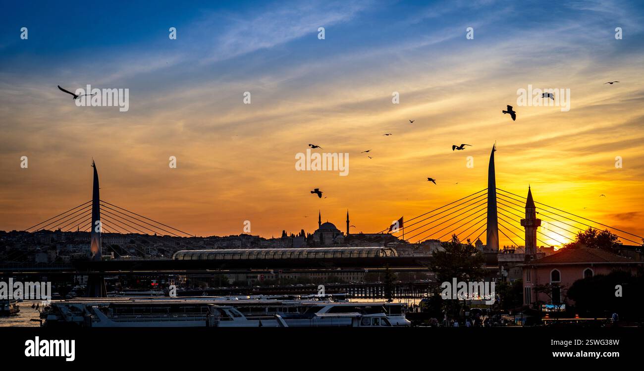 Ein atemberaubender Sonnenuntergang über Istanbul mit Silhouetten von Brücken, Moscheen und Vögeln, die am Himmel fliegen. Die warmen Farben der Sonnen Stockfoto