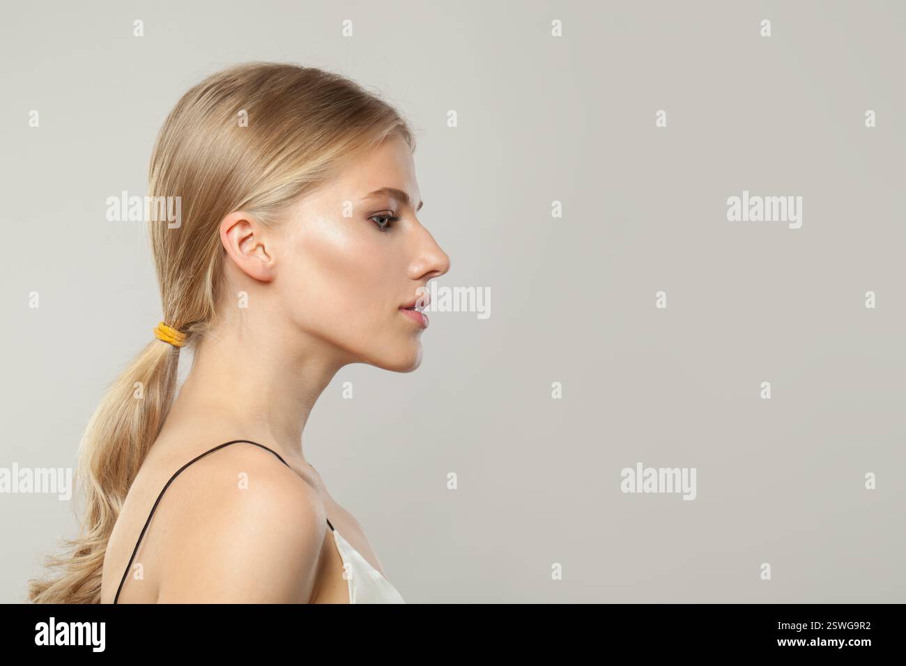 Schönes junges blondes weibliches Modell mit klarer Haut, weichem Make-up und gesundem Haar und natürlichem emotionalem Ausdruck Porträt aufgenommen. Profil des blonden Arbeitsbereichs Stockfoto