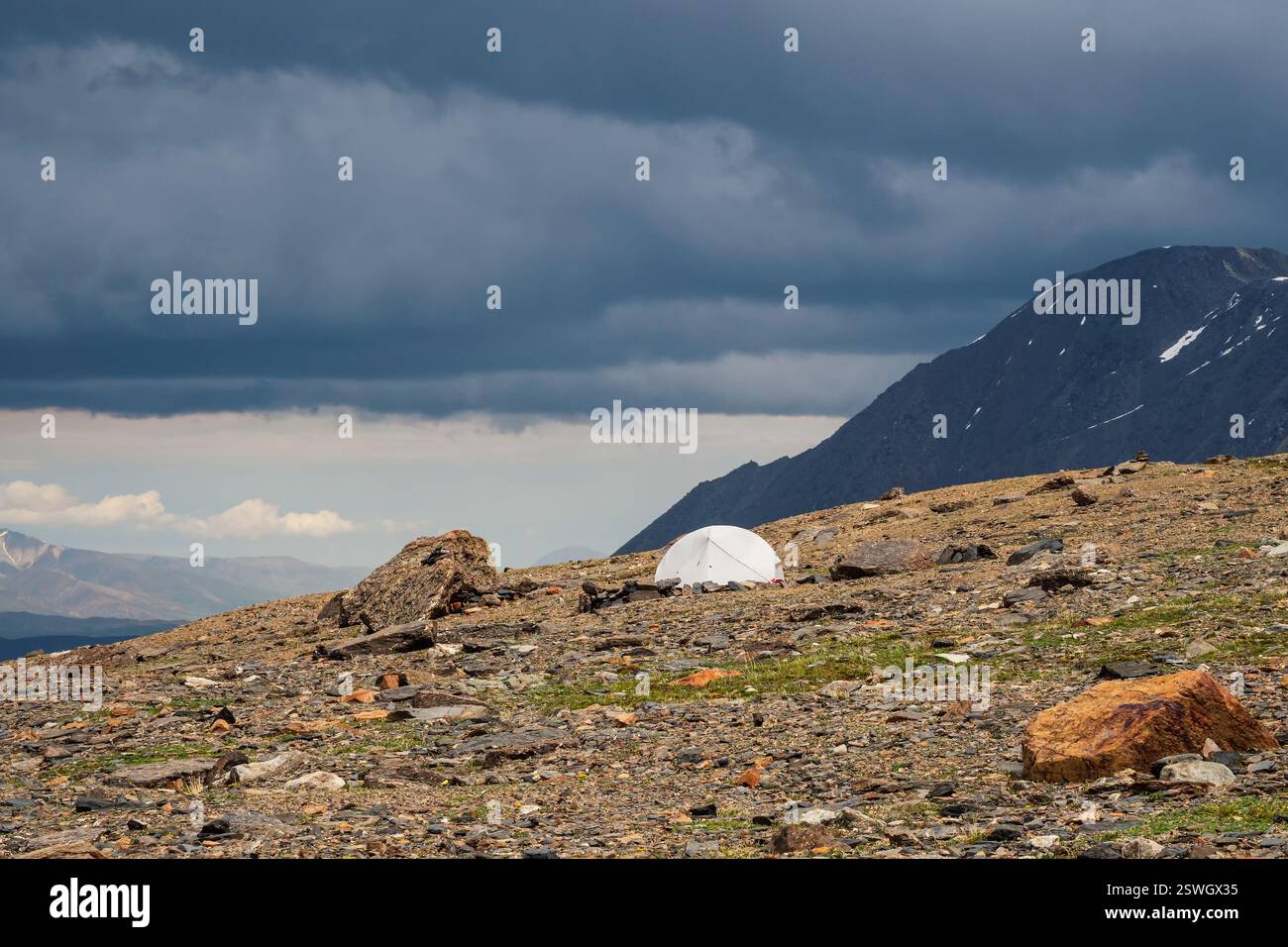 Sommercamping in den Bergen. Helle Alpenlandschaft mit einsamem weißem Zelt in sehr hoher Höhe mit Blick auf den hohen Berg in d Stockfoto