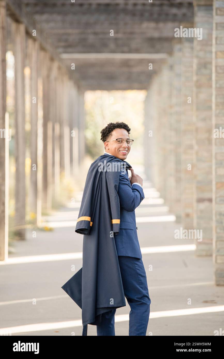 Der Absolvent geht weg und hält ein Kleid Stockfoto