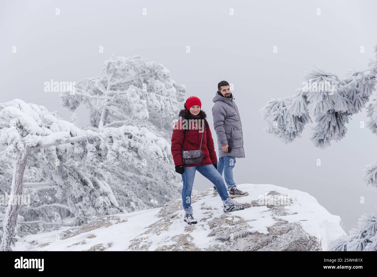 Frau mittleren Alters und junger erwachsener Mann auf einer Klippe vor milchweißem Himmel Stockfoto