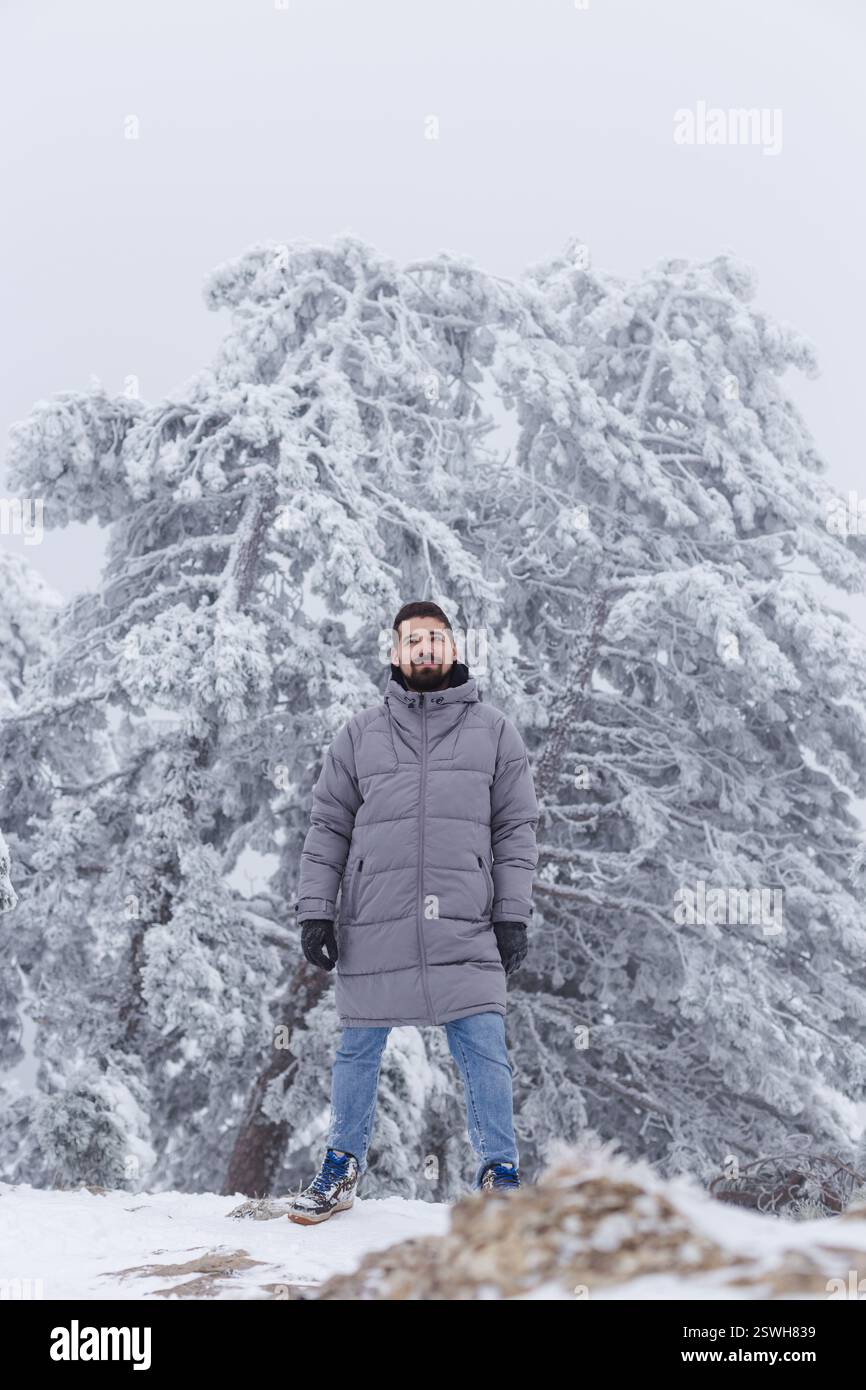 Winterwanderer vor eisbedeckten Kiefern und milchig nebeligen Himmel Stockfoto