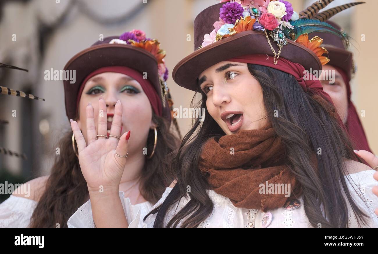 Das Bild zeigt zwei Personen, wahrscheinlich bei einer Veranstaltung wie einem Festival oder einer Themenversammlung. Sie tragen Kostüme mit verzierten Hüten Stockfoto