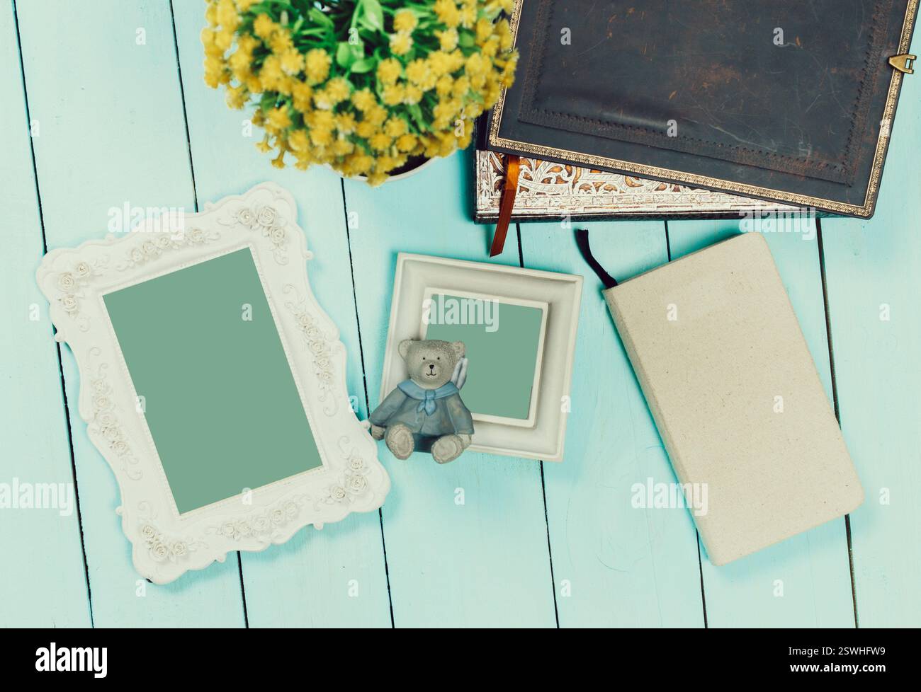 Dekorative Gegenstände auf einem blauen Holztisch mit Blumen, Tagebüchern und einem Kuschelbären in gemütlicher Atmosphäre Stockfoto