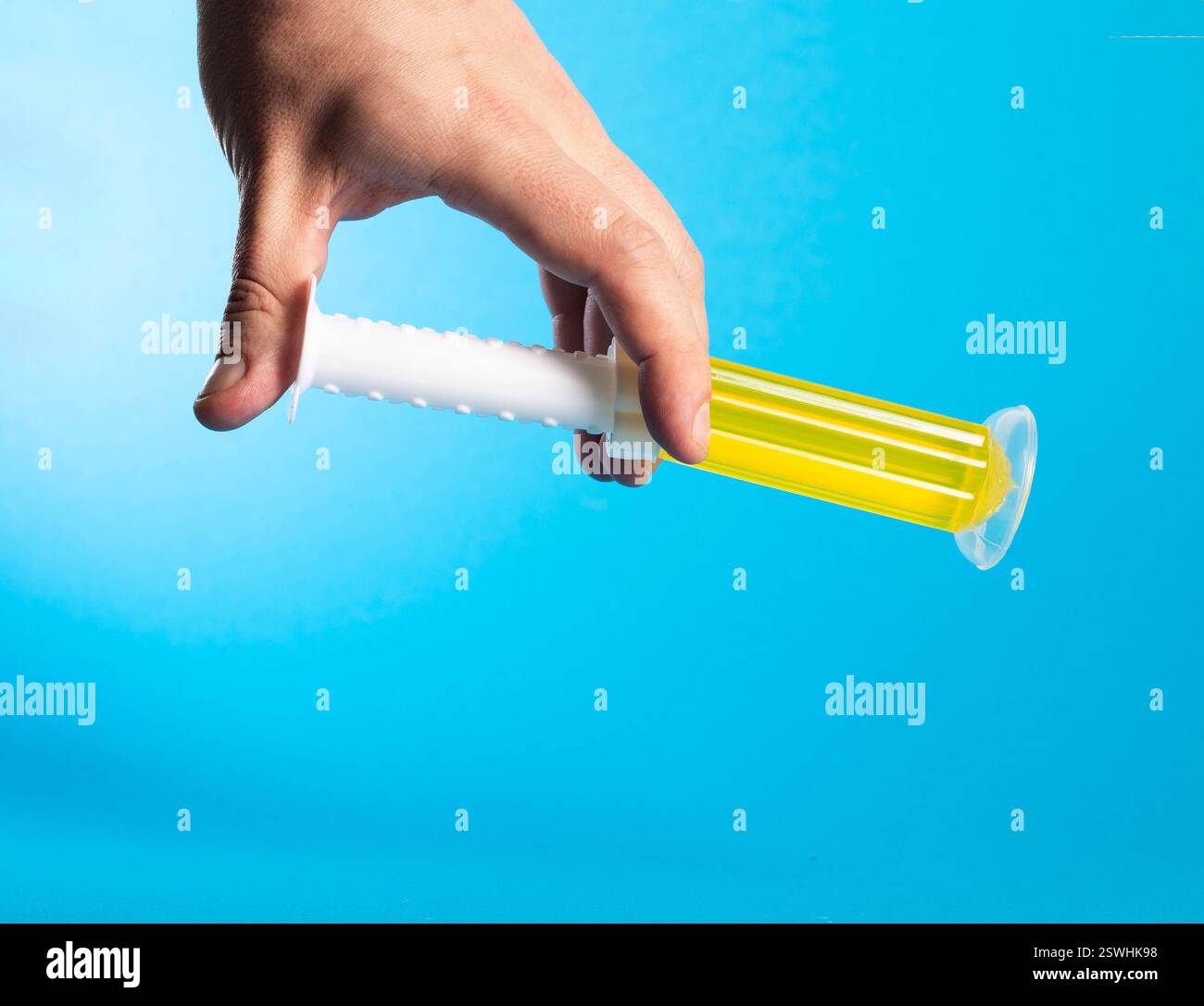 Hand mit Desinfektionsreiniger gelbes Gel auf blauem Hintergrund. Kopierbereich für Text Stockfoto
