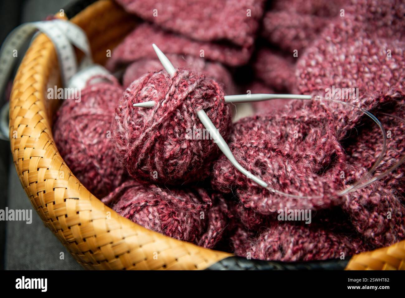 Garne, Stricknadeln und Musterprobe im Korb auf dem Sofa. Nahaufnahme Stockfoto