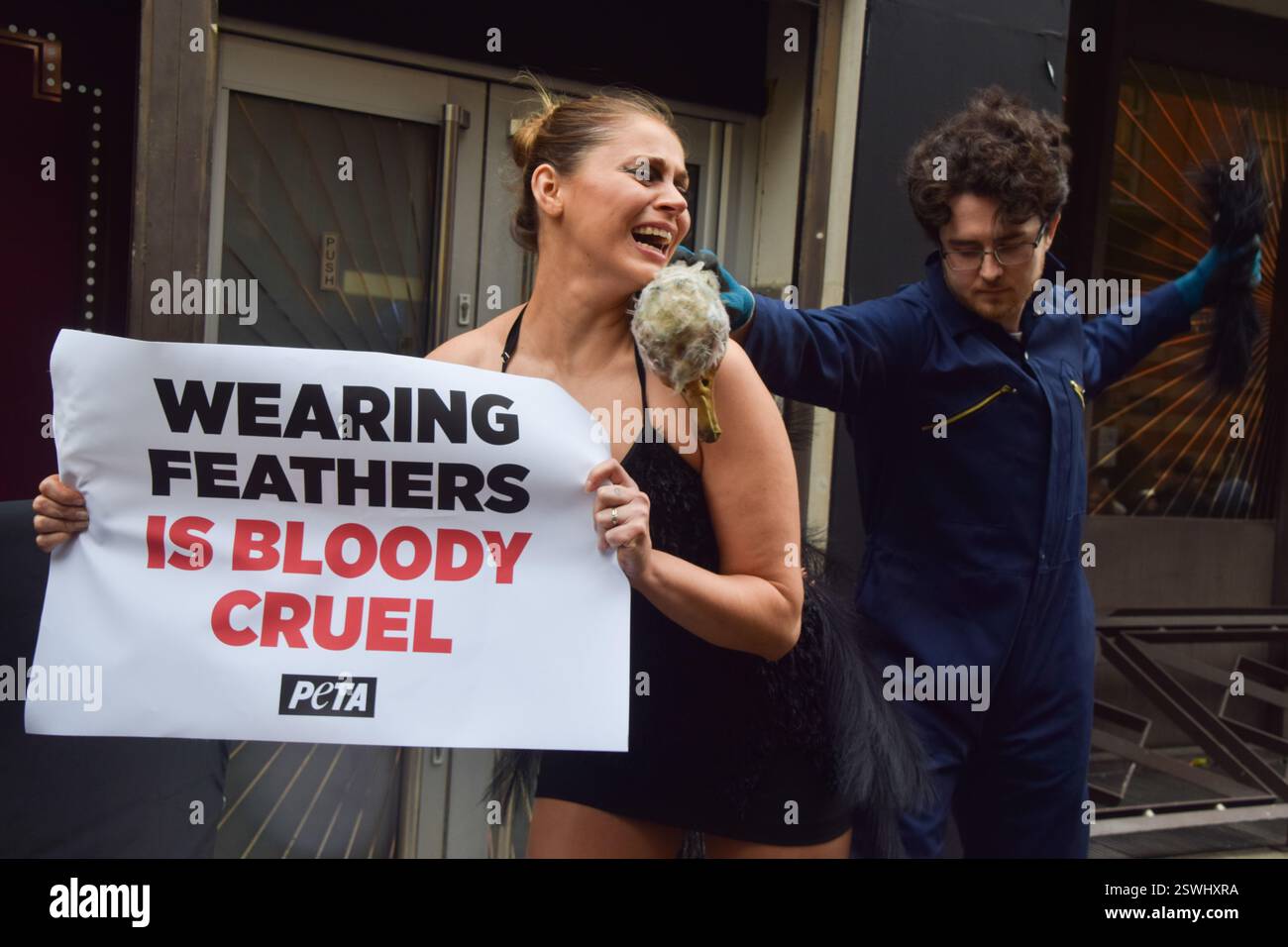 London, Großbritannien. Februar 2025. Eine PETA-Aktivistin, die als Strauß verkleidet ist, lässt ihre Federn vor der London Fashion Week NEWGEN Show Space on the Strand „heftig zupfen“. Die Aktion ist Teil der laufenden PETA-Kampagne gegen den Einsatz von Federn in der Mode. Quelle: Vuk Valcic/Alamy Live News Stockfoto