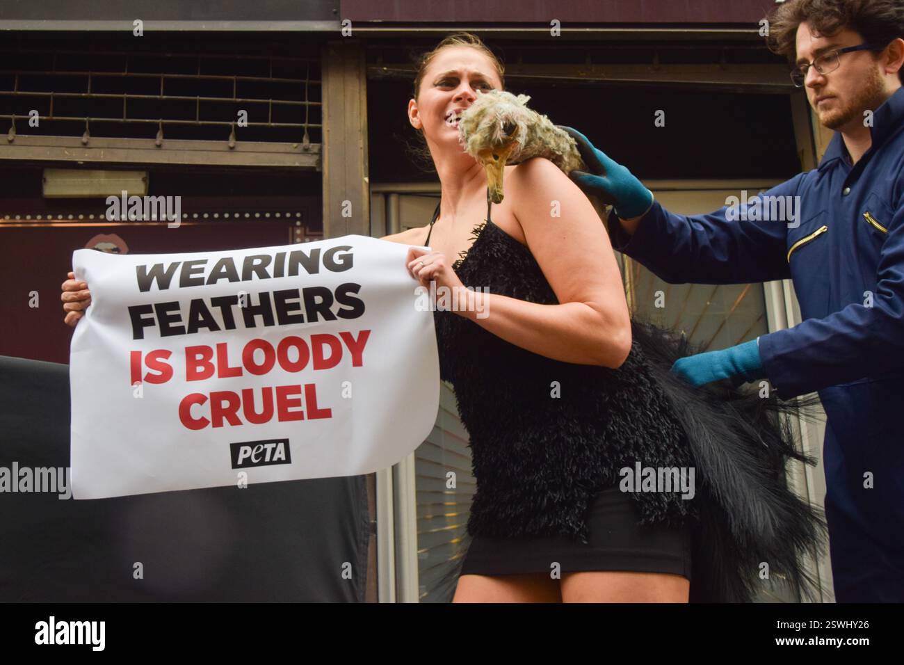 London, Großbritannien. Februar 2025. Eine PETA-Aktivistin, die als Strauß verkleidet ist, lässt ihre Federn vor der London Fashion Week NEWGEN Show Space on the Strand „heftig zupfen“. Die Aktion ist Teil der laufenden PETA-Kampagne gegen den Einsatz von Federn in der Mode. Quelle: Vuk Valcic/Alamy Live News Stockfoto