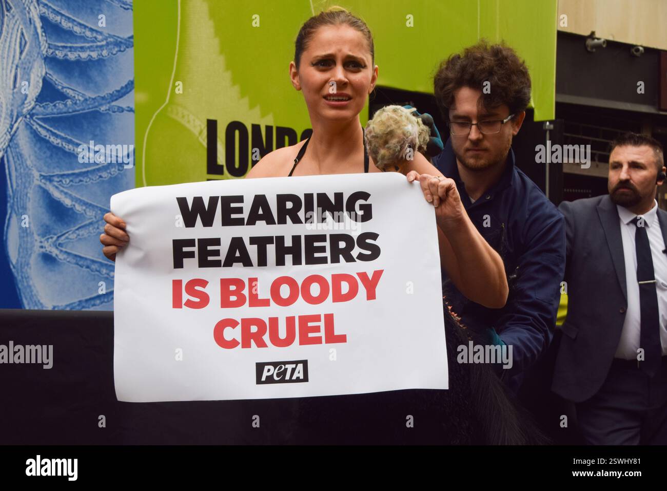 London, Großbritannien. Februar 2025. Eine PETA-Aktivistin, die als Strauß verkleidet ist, lässt ihre Federn vor der London Fashion Week NEWGEN Show Space on the Strand „heftig zupfen“. Die Aktion ist Teil der laufenden PETA-Kampagne gegen den Einsatz von Federn in der Mode. Quelle: Vuk Valcic/Alamy Live News Stockfoto