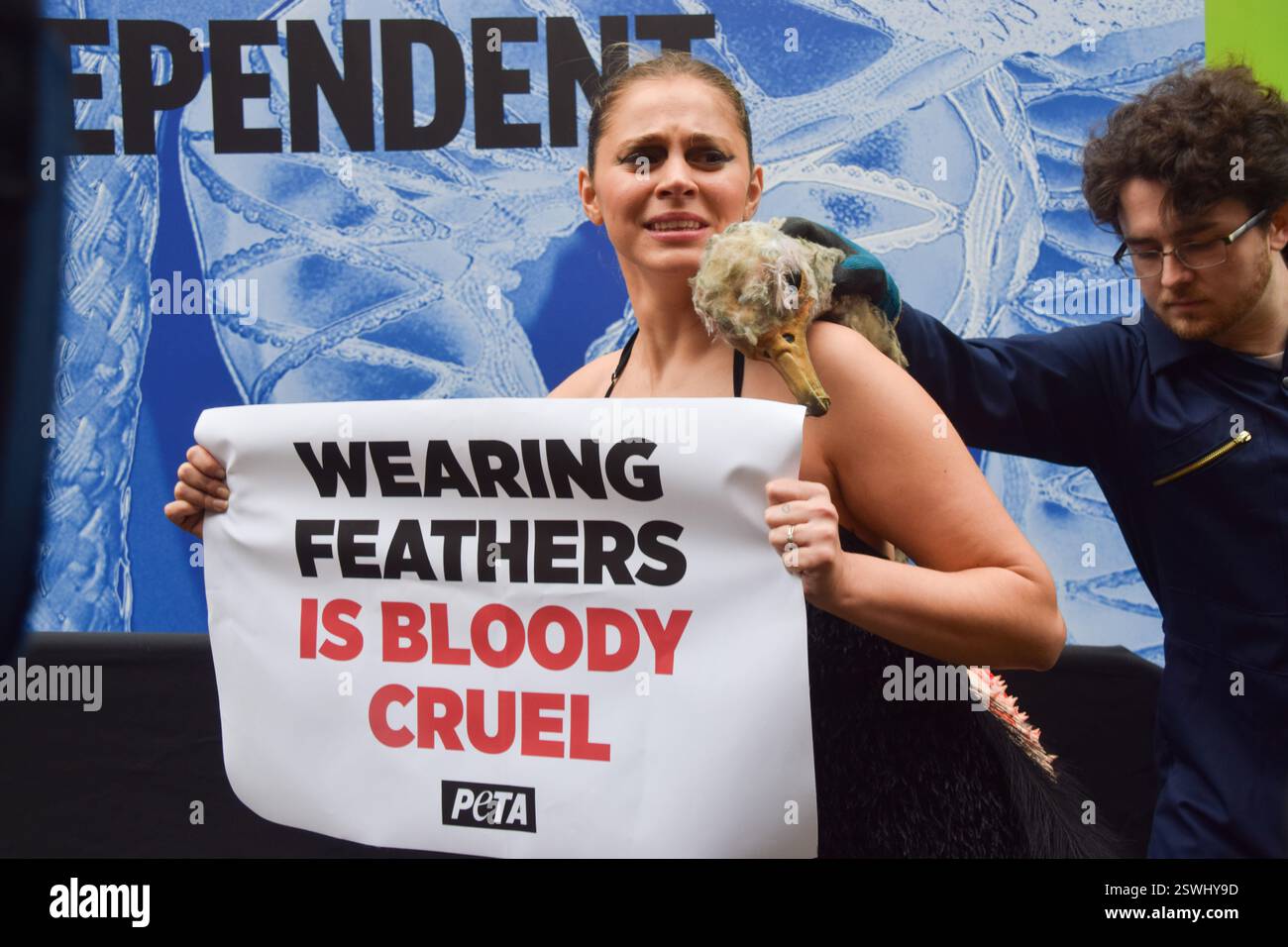 London, Großbritannien. Februar 2025. Eine PETA-Aktivistin, die als Strauß verkleidet ist, lässt ihre Federn vor der London Fashion Week NEWGEN Show Space on the Strand „heftig zupfen“. Die Aktion ist Teil der laufenden PETA-Kampagne gegen den Einsatz von Federn in der Mode. Quelle: Vuk Valcic/Alamy Live News Stockfoto