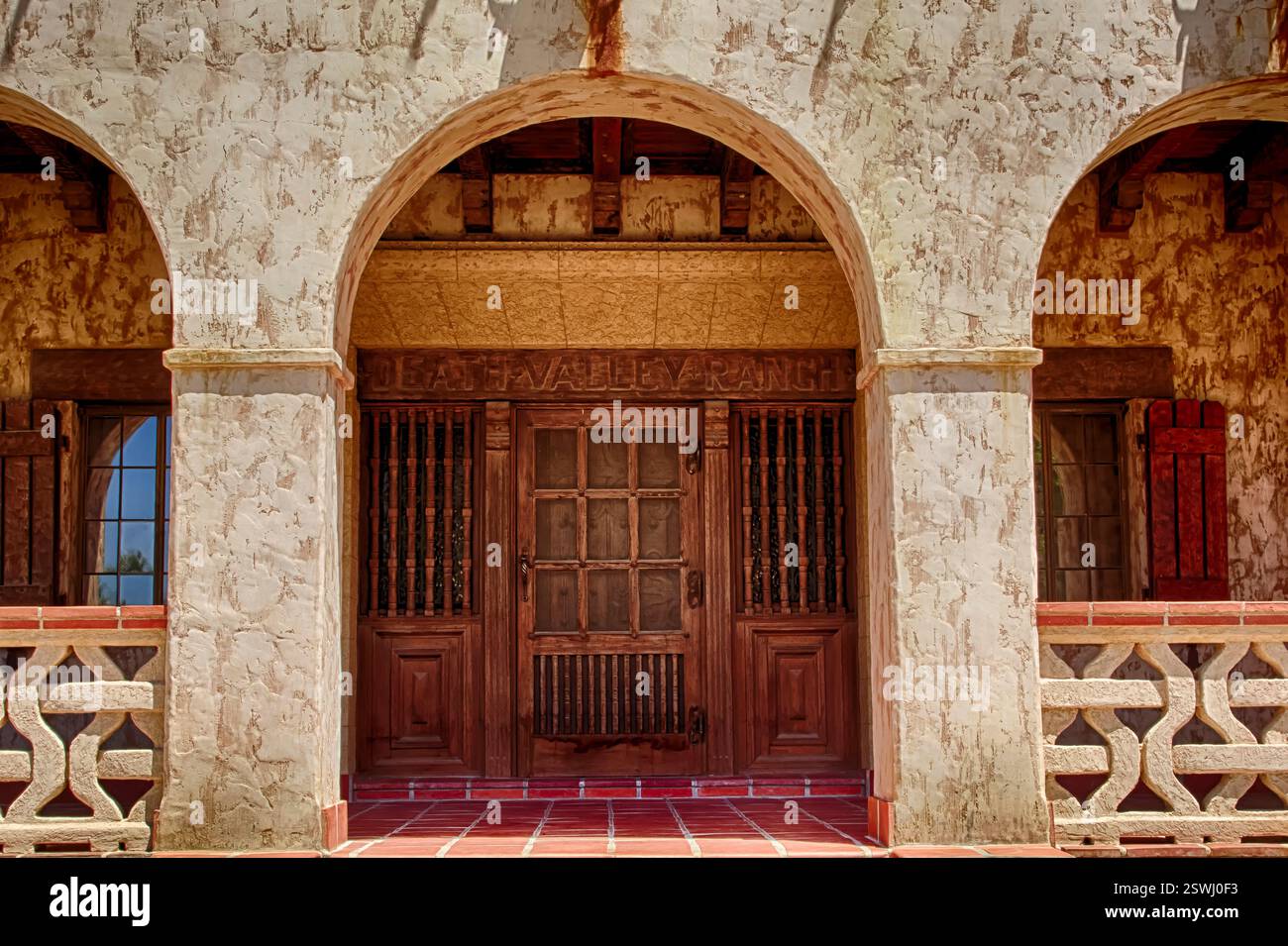 Großer Torbogen mit einer Holztür. An der Tür ist ein Bildschirm drauf. Der Bogengang ist aus Stein Stockfoto