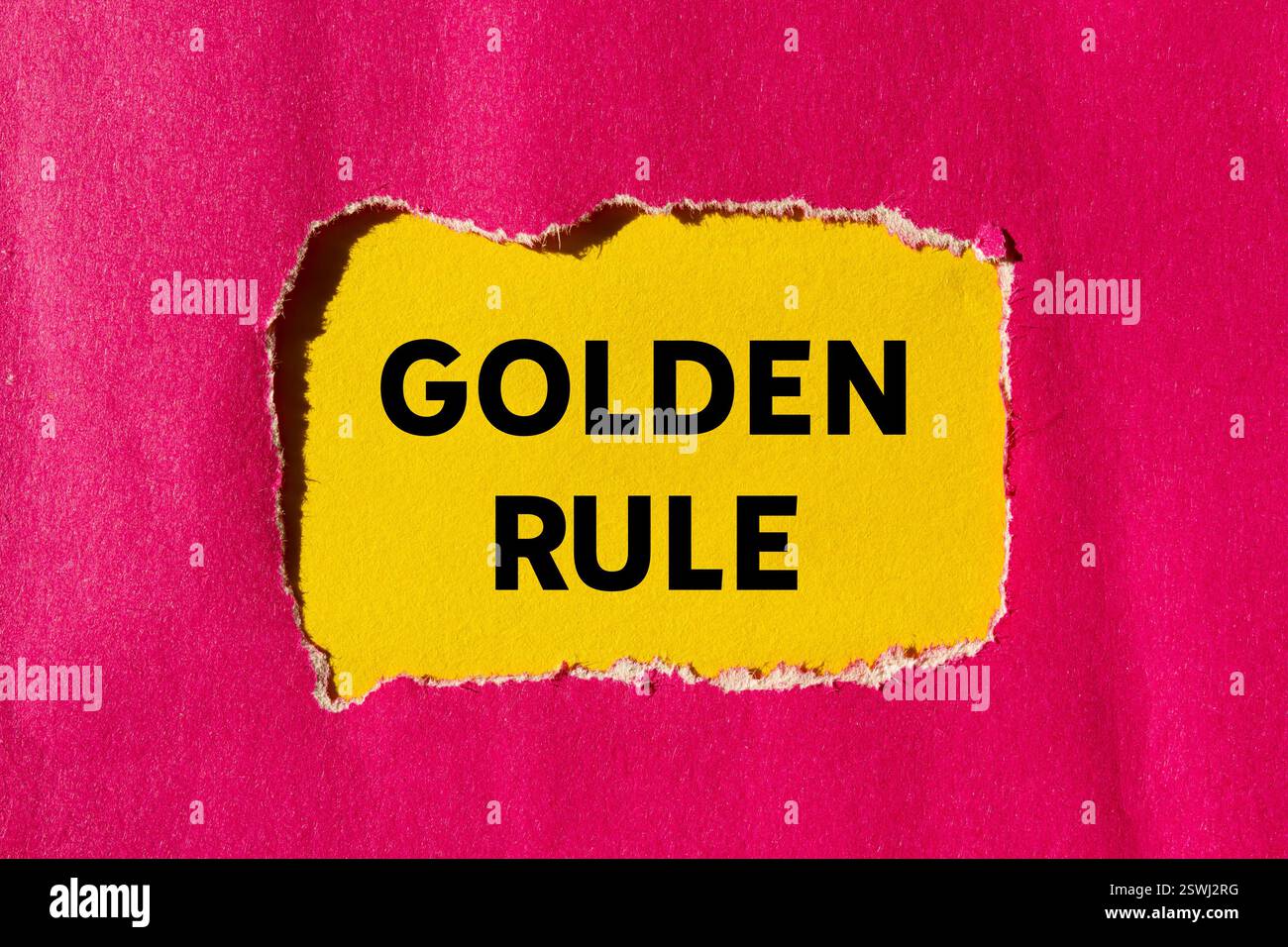 Goldene Regelnachricht auf gerissenem rosa Papier auf gelbem Hintergrund. Konzeptionelles goldenes Regelsymbol. Kopierbereich. Stockfoto