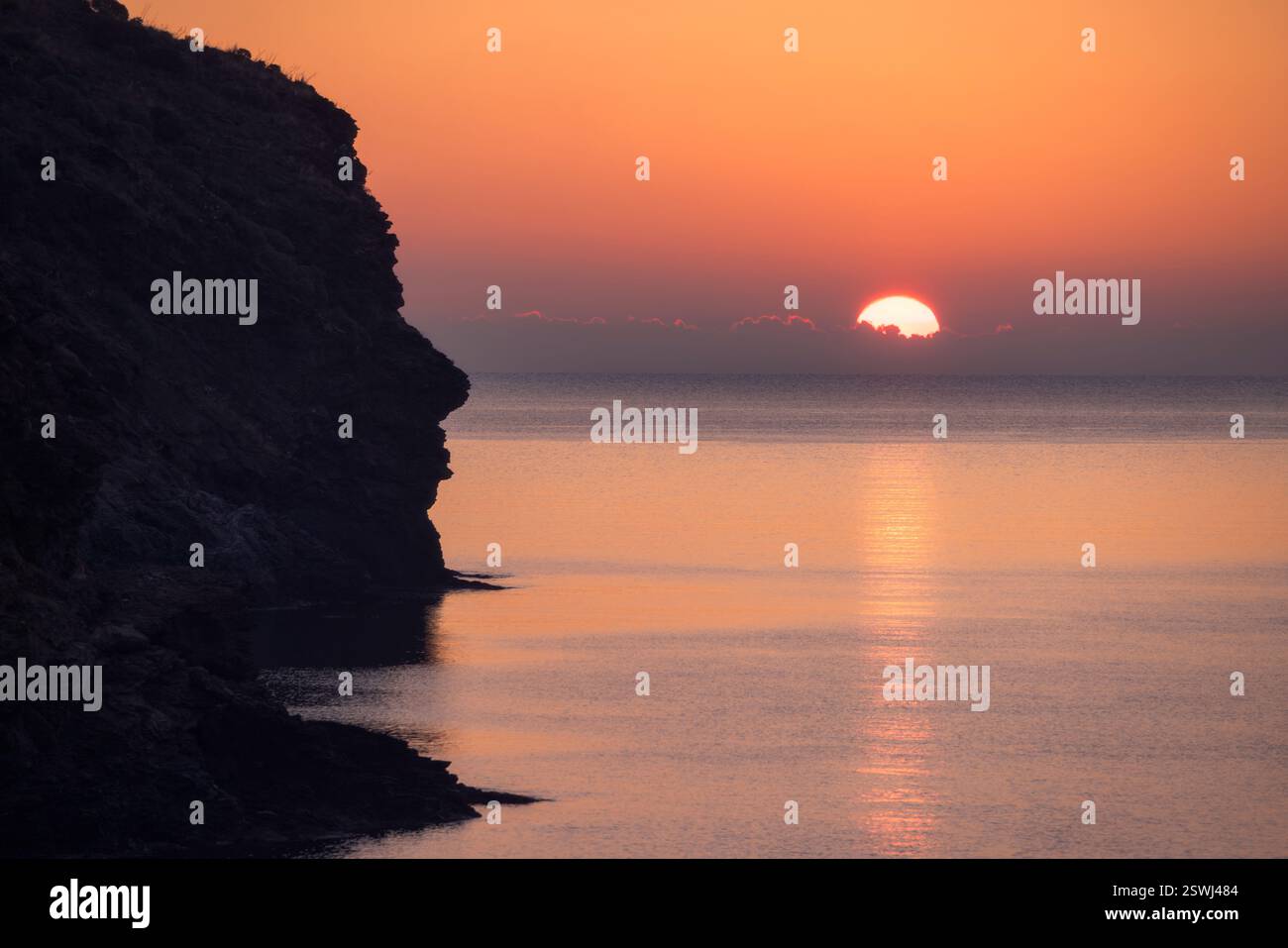 Goldene Farbtöne erheben sich über dem ruhigen Wasser der Cala Joncols und heißen einen brandneuen Tag in Kataloniens heiterer Schönheit willkommen. Stockfoto