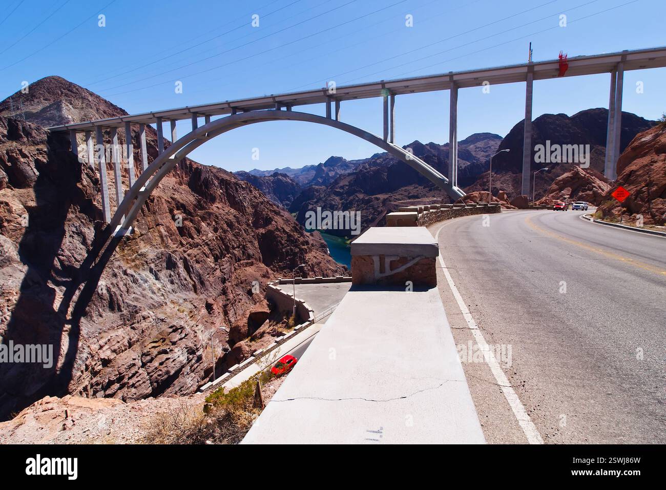 Die Brücke überspannt einen Fluss und ist von Bergen umgeben. Die Brücke ist ein großer Bogen und liegt an einer Straße Stockfoto