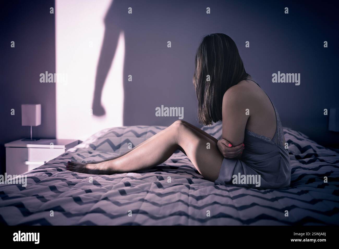 Gewalttätigkeit in toxischer Beziehung. Häusliche Gewalt. Opfer eines Psychopathen-wahnsinnigen Ehepartners. Frau im Bett. Schatten einer wütenden betrunkenen Mann Faust. Stockfoto