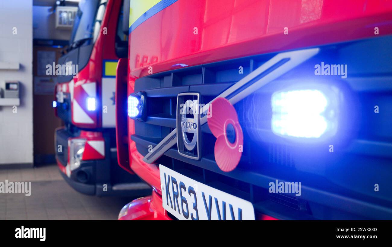 Feuerwehrfahrzeuge in der Feuerwache mit eingeschaltetem Licht, Nahaufnahme einschließlich Gedenk-Mohn. - Cumbria Fire and Rescue Service, Penrith, England Stockfoto