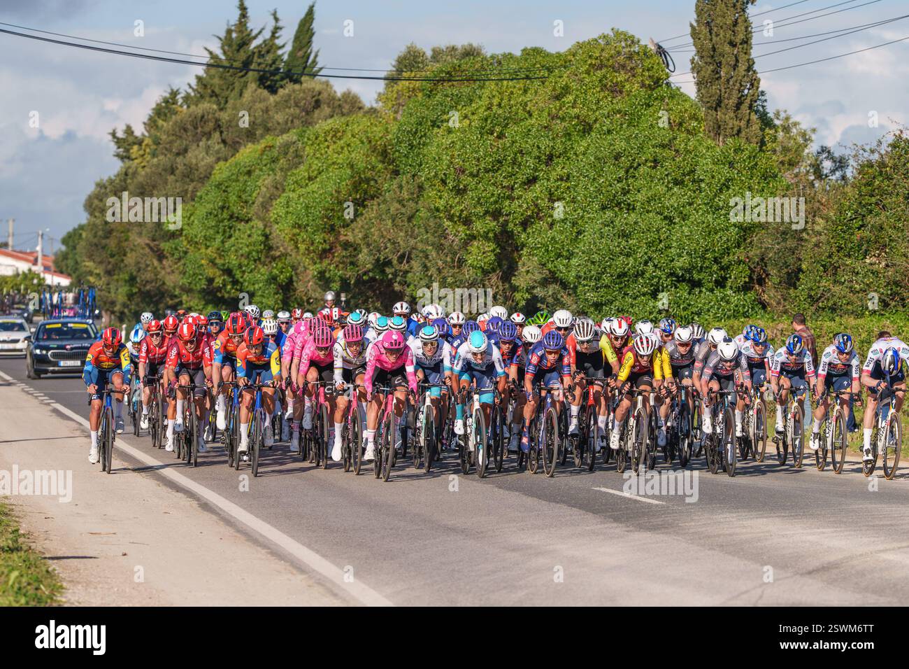 Tavira, Portugal, 21. Februar 2025.Radfahrer sind in einem Feldrennen auf einer kurvenreichen Straße eng gepackt. Die Volta ao Algarve, Rennradrennen. Stufe 3, Stockfoto