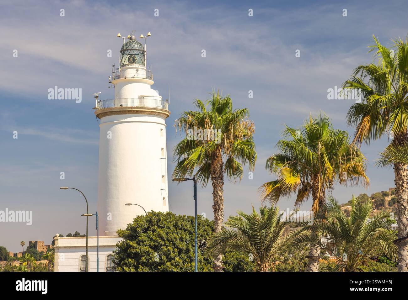 Malaga, Küstenstadt in Andalusien, Spanien, Europa. Der weiße Leuchtturm steht hoch vor einem hellblauen Himmel, umgeben von üppigen Palmen. Malerisch Stockfoto