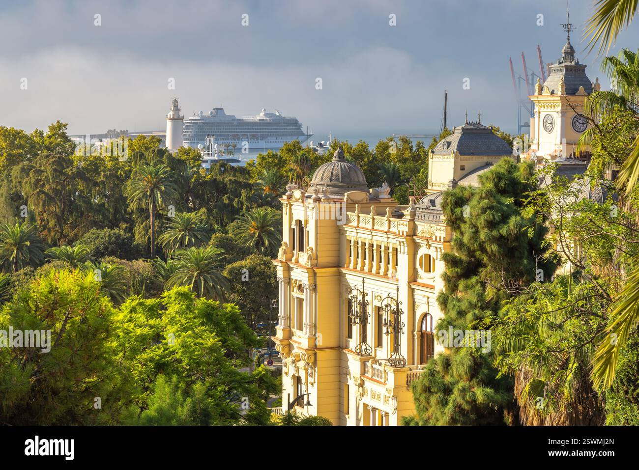 Malaga, Küstenstadt in Andalusien, Spanien, Europa. Blick auf die Küstenstadt: großes Gebäude, üppiger Park und ein Kreuzfahrtschiff am Hafen. Stockfoto