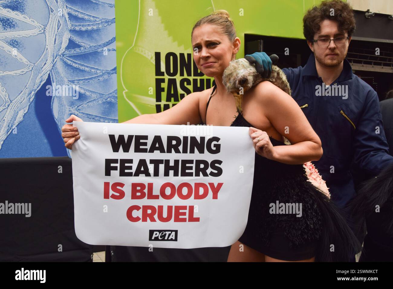 London, Großbritannien. Februar 2025. Eine PETA-Aktivistin, die als Strauß verkleidet ist, lässt ihre Federn vor der London Fashion Week NEWGEN Show Space on the Strand „heftig zupfen“. Die Aktion ist Teil der laufenden PETA-Kampagne gegen den Einsatz von Federn in der Mode. Quelle: Vuk Valcic/Alamy Live News Stockfoto