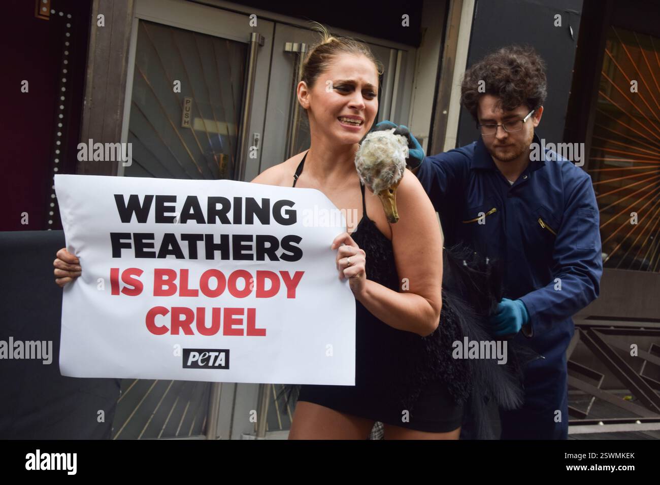 London, Großbritannien. Februar 2025. Eine PETA-Aktivistin, die als Strauß verkleidet ist, lässt ihre Federn vor der London Fashion Week NEWGEN Show Space on the Strand „heftig zupfen“. Die Aktion ist Teil der laufenden PETA-Kampagne gegen den Einsatz von Federn in der Mode. Quelle: Vuk Valcic/Alamy Live News Stockfoto