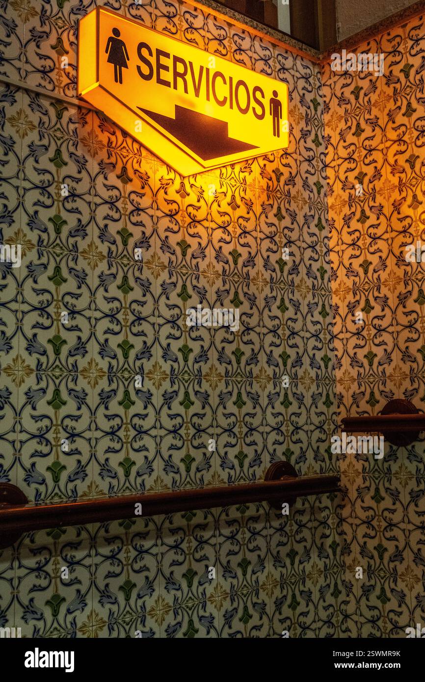 Helles Toilettenschild vor dekorativer gefliester Wand in einem öffentlichen Ambiente, Jaen, Andalusien. Stockfoto