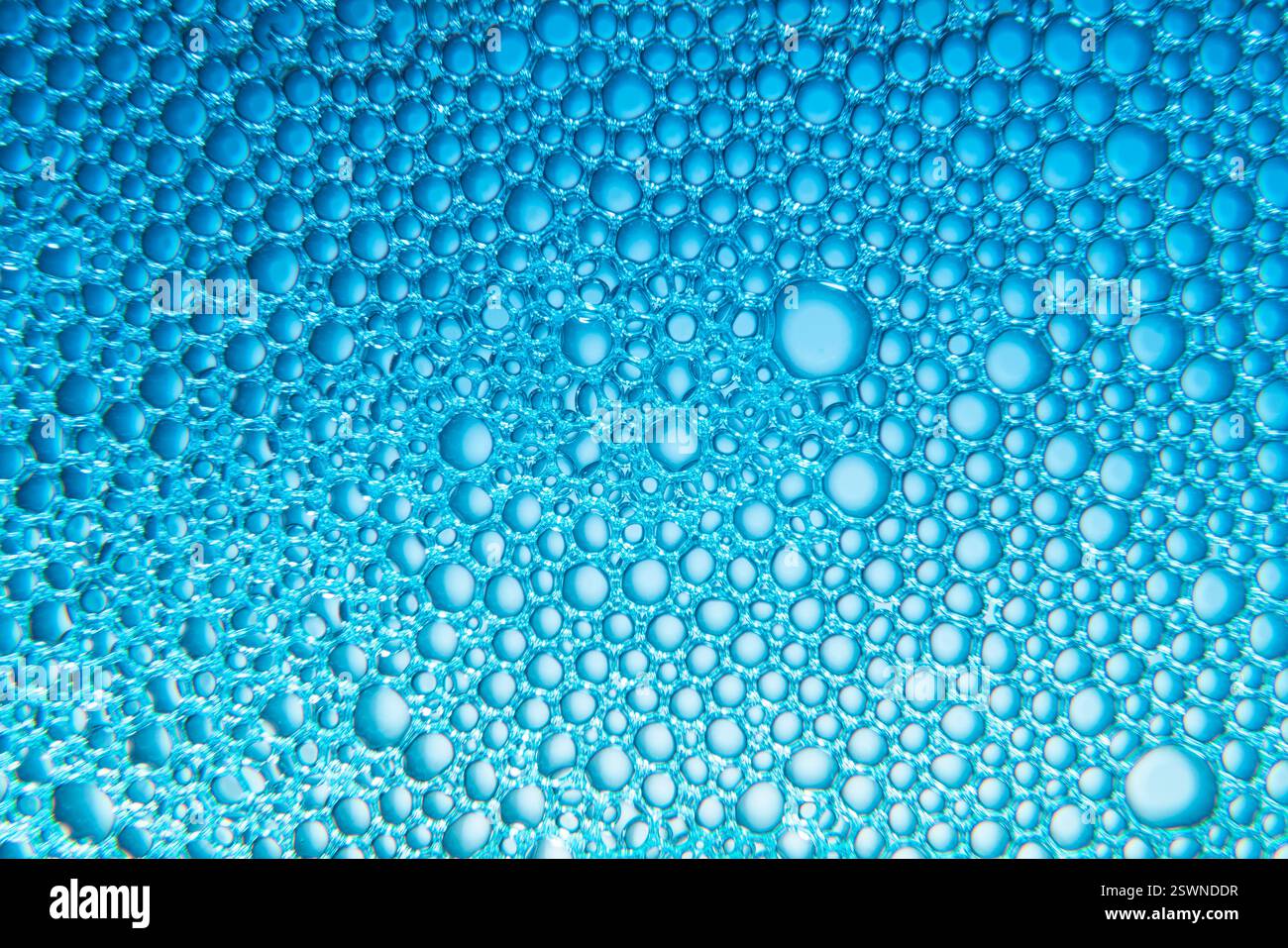 Textur von Seifenblasen und Wasser mit blauem Licht auf hellblauem Hintergrund Stockfoto