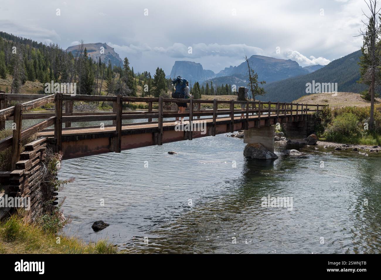 Rucksacktouristen auf der Fußgängerbrücke über den oberen Green River in Wyomings Wind River Range. Stockfoto