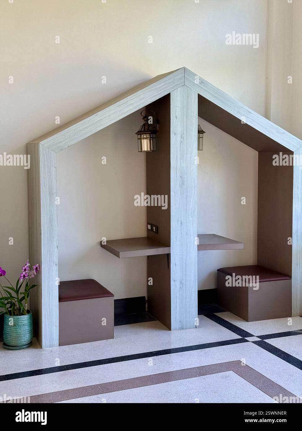 Cozy Office Nook in House-Shaped Design Ein moderner und minimalistischer Arbeitsbereich mit Holznischen, die wie eine häusliche Silhouette geformt sind. - Smartphone-aufgenommenes Stockfoto