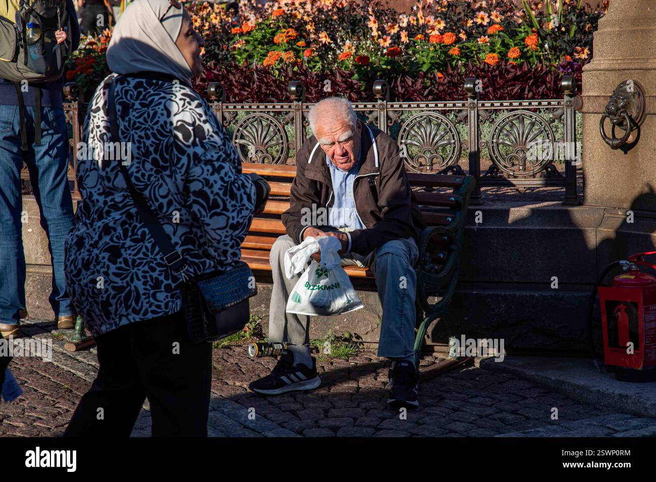 Ein älterer Mann mit starken Augenbrauen sitzt auf einer Bank auf dem Senatsplatz in Helsinki, Finnland Stockfoto