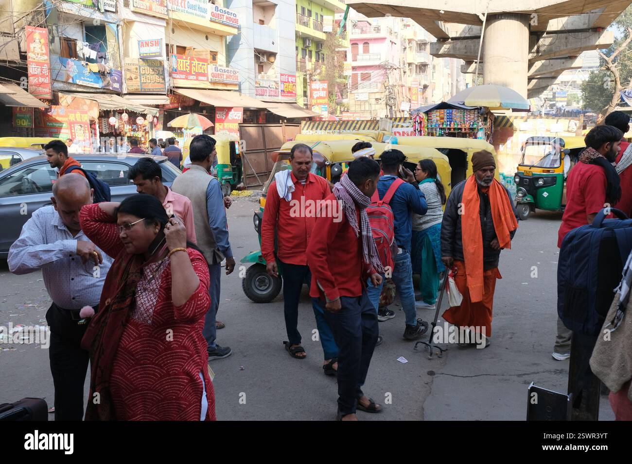 Passagiere stehen auf einer belebten Straße in der Nähe des Eingangs zum Bahnhof Hazrat Nizamuddin in der indischen Hauptstadt Delhi herum Stockfoto