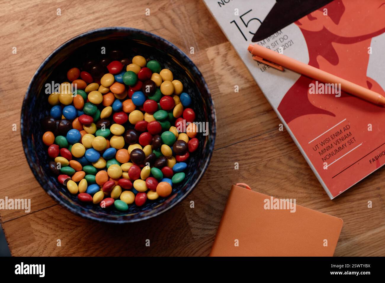 Flache Schüssel aus Keramik gefüllt mit runden, beschichteten Süßigkeiten in verschiedenen Farben auf dem Couchtisch im Wohnzimmer, Kopierraum Stockfoto