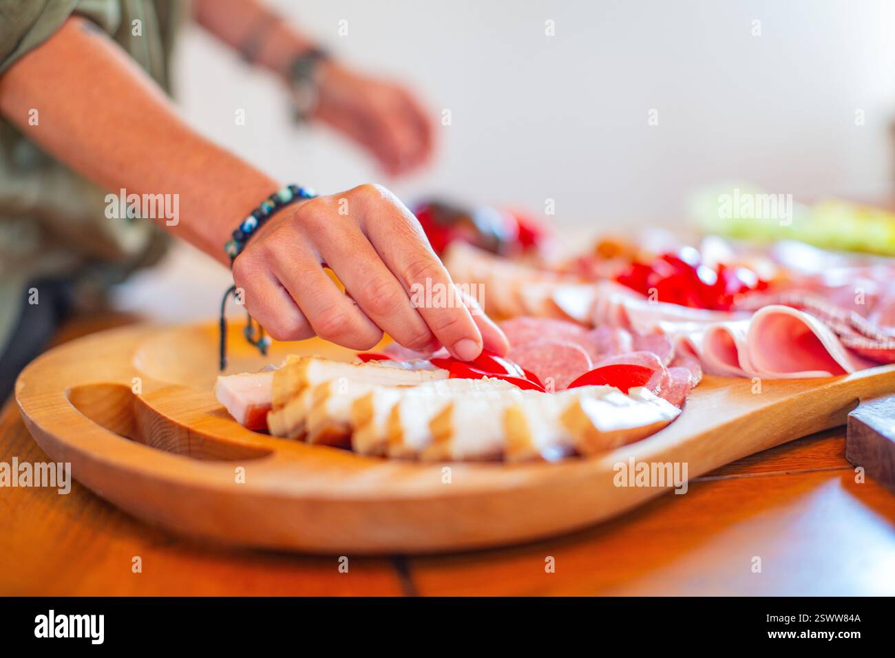 Nahaufnahme einer Person, die Stücke auf einer lebendigen Essensplatte arrangiert und auswählt. Stockfoto