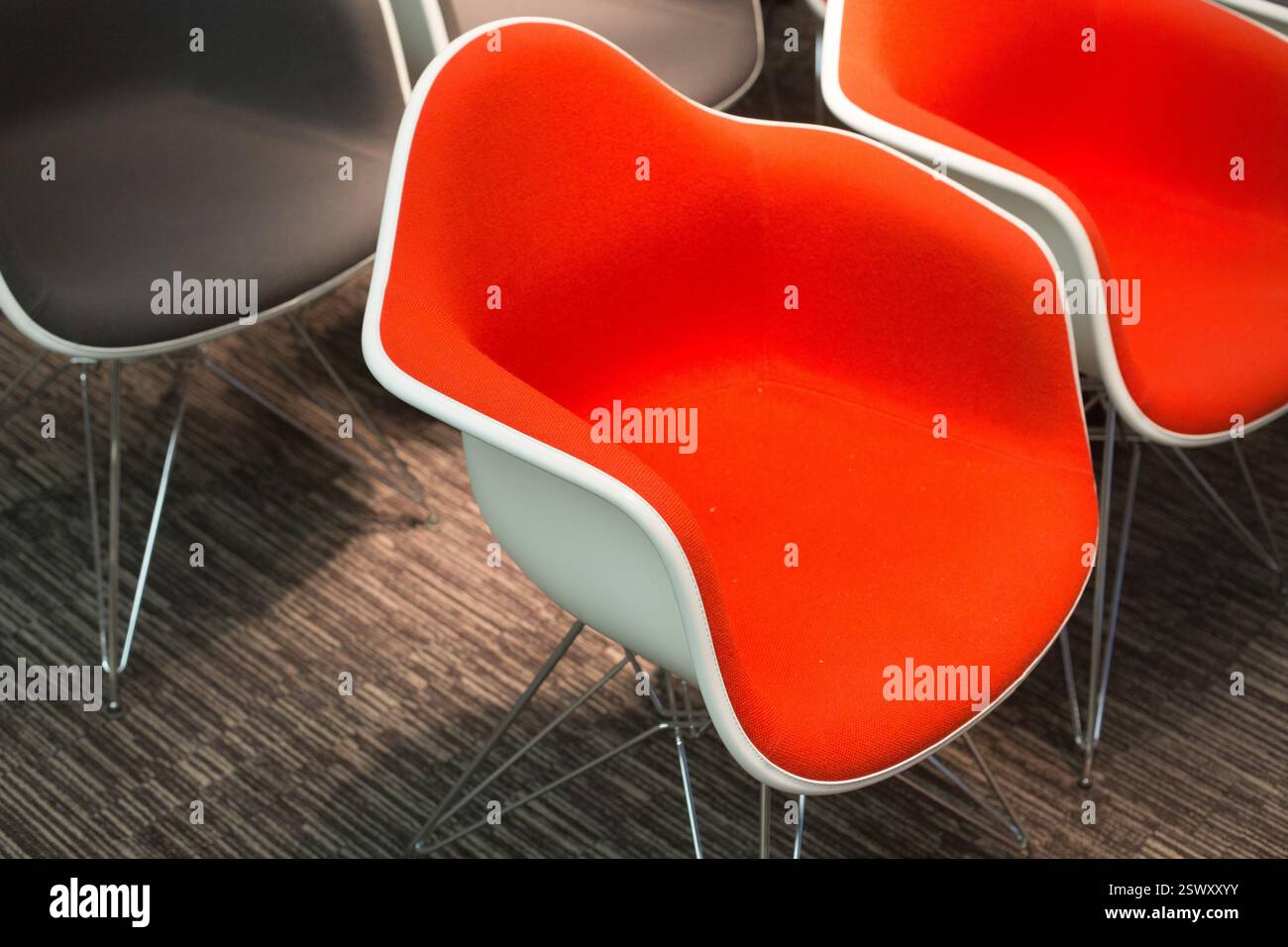 Orangefarbene und schwarze Stühle, wahrscheinlich in einem Besprechungsraum oder Büro in einem modernen Gebäude. Stockfoto