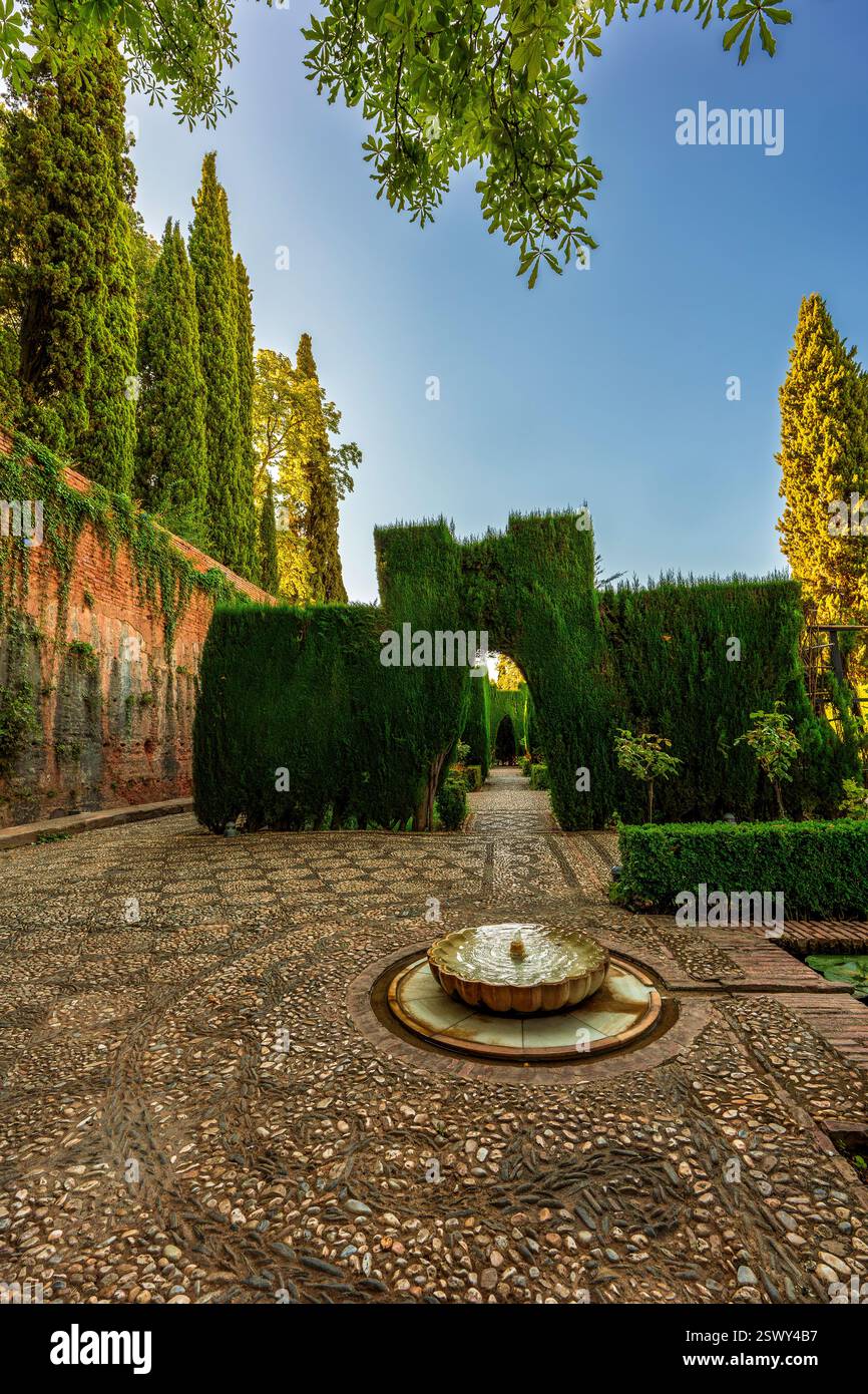 Ruhiger maurischer Innenhof mit lebendigem Zypressenbogen, Kieselmosaik und zauberhaftem Brunnen im legendären Generalife Garden Sanctuary im historischen Granada Stockfoto
