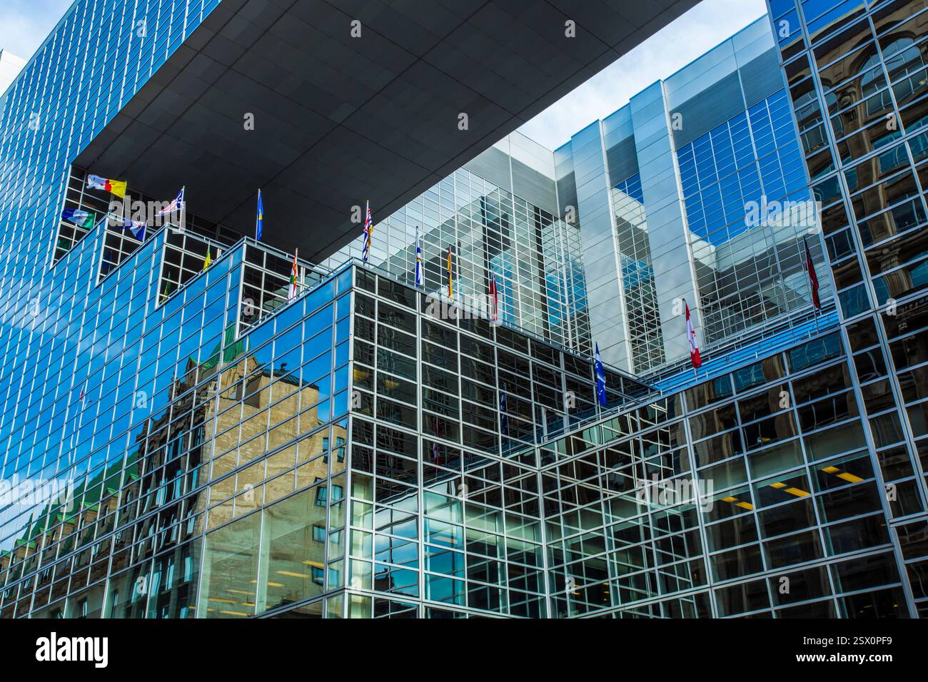 Großes Gebäude mit Glasdach und vielen Flaggen darauf. Die Flaggen haben unterschiedliche Farben und Größen Stockfoto