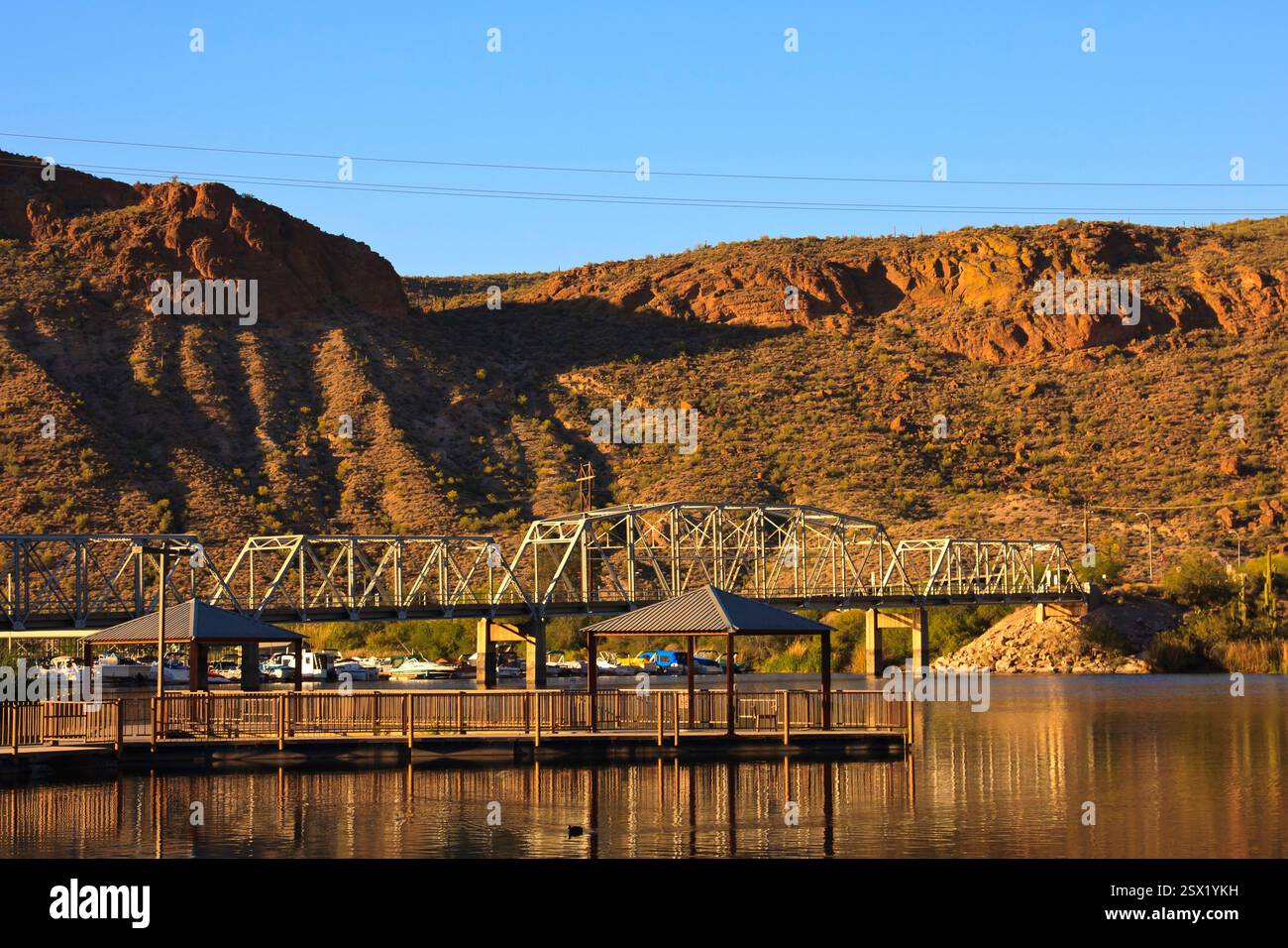 Die Brücke überspannt ein Gewässer mit Blick auf die Berge im Hintergrund. Die Brücke ist von einem Dock und einem Pavillon umgeben Stockfoto