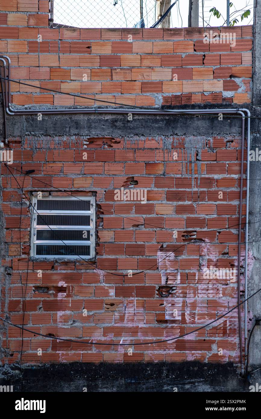 Ziegelmauer mit sichtbaren Sanitäranlagen in der Gasse Favela, armseliges Viertel von Diadema, Randstadt São Paulo, Brasilien Stockfoto