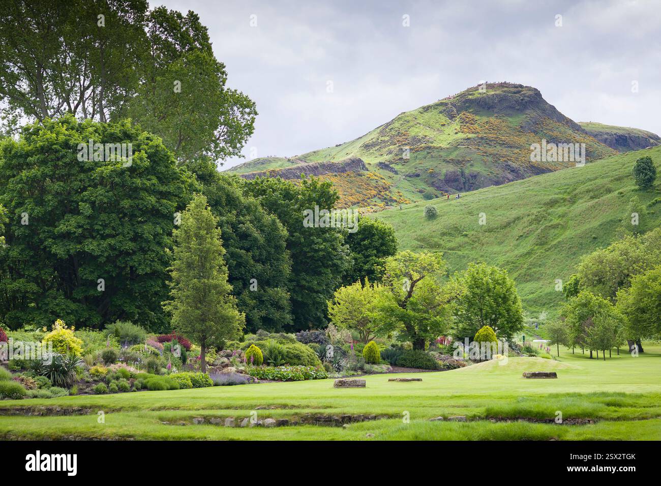 Üppige grüne Gärten des Holyroodhouse Palace in Edinburgh, Großbritannien, mit Arthurs Sitz im Hintergrund, die die Natur und landschaftliche Schönheit von Scotlands zeigen. Stockfoto