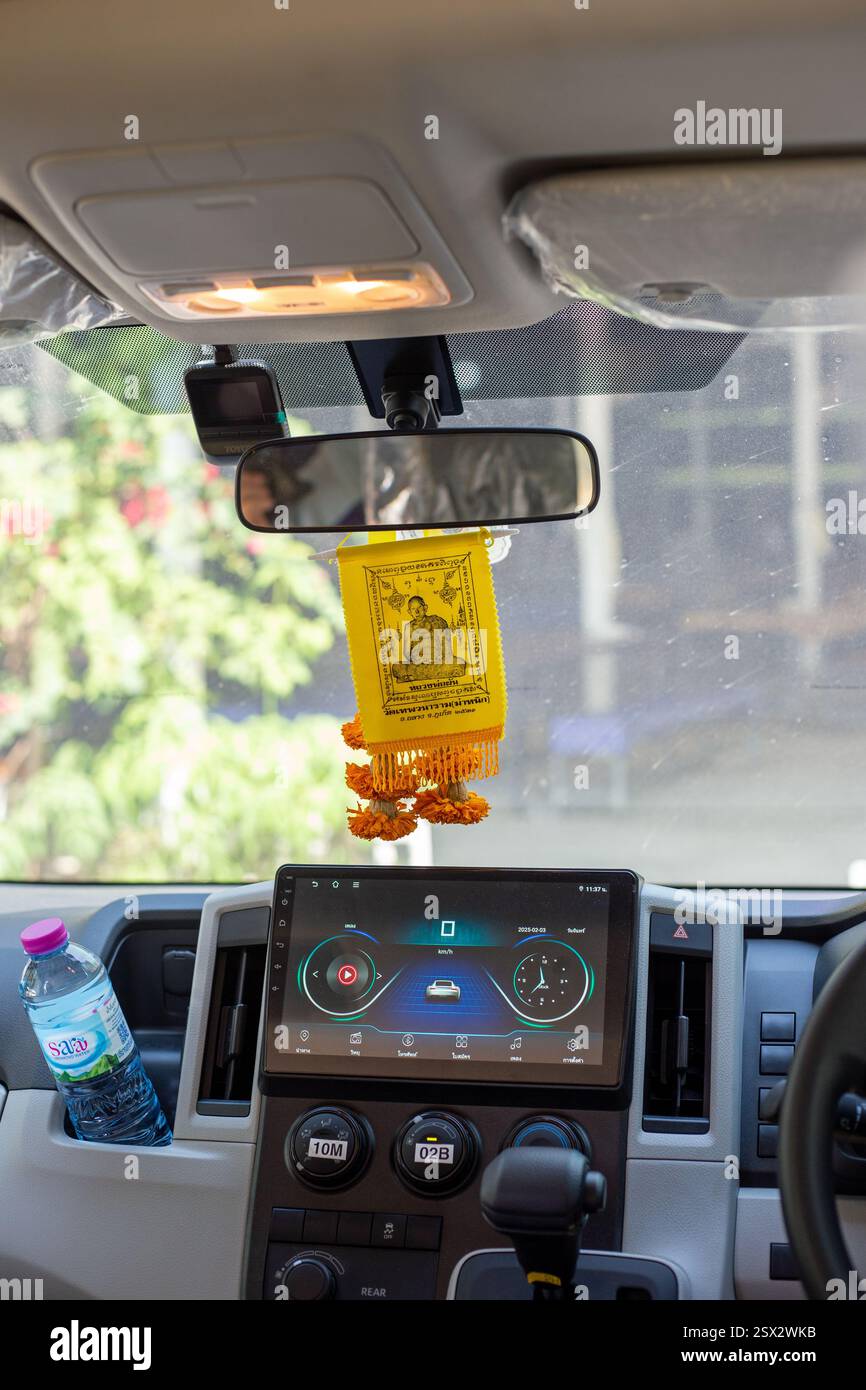 Phuket, Thailand, 3. Februar 2025, ein Blick auf das Taxi eines Minibusses zeigt kulturelle Einflüsse, wobei buddhistische Gebete vom Spiegel hängen. Stockfoto