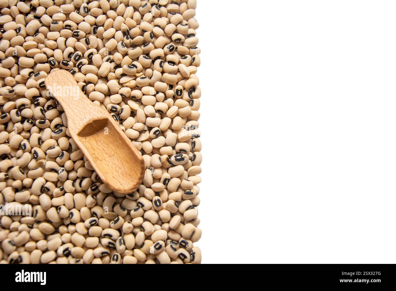 Haufen Schwarzäugiger Erbsen mit Holzlöffel, zur Hälfte auf weißem Kopierraum Stockfoto