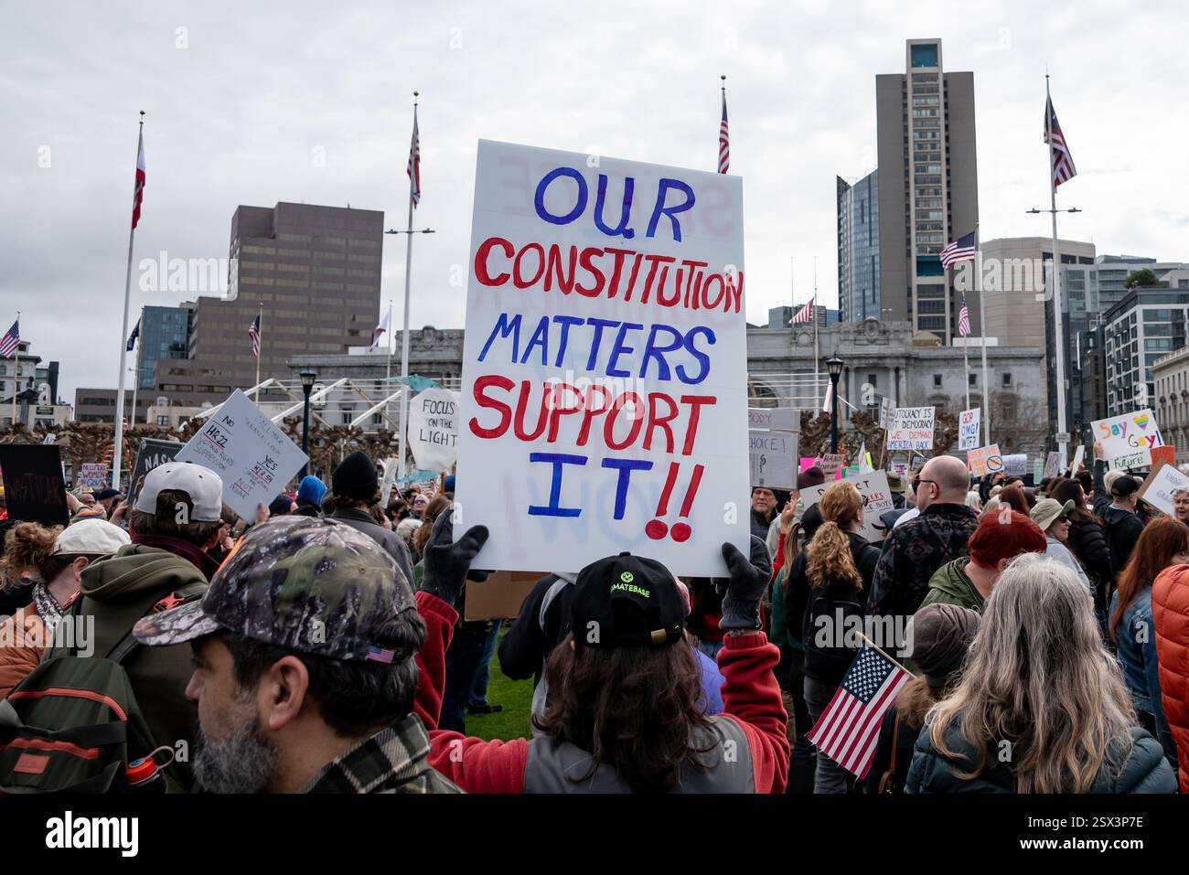 San Francisco, Kalifornien, USA, 17. Februar 2025. Hunderte versammeln sich vor dem Rathaus von San Francisco bei einem „No Kings“-Protest zum Präsidenten-Tag gegen die jüngsten Befehle von Präsident Donald Trump und die Maßnahmen des DOGE-Teams von Elon Musk. Über der Menge steht auf einem Schild: "Unsere Verfassung ist wichtig. Unterstützen!“ Quelle: Shelly Rivoli/Alamy Stockfoto