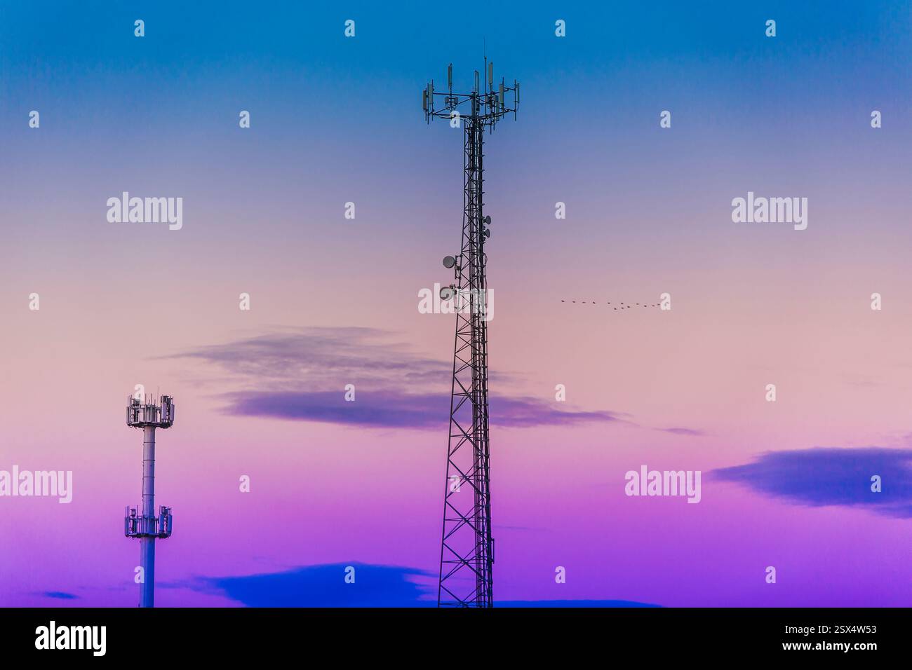 Hoher Turm mit violettem und blauem Himmel im Hintergrund. Im Hintergrund befinden sich zwei Türme Stockfoto